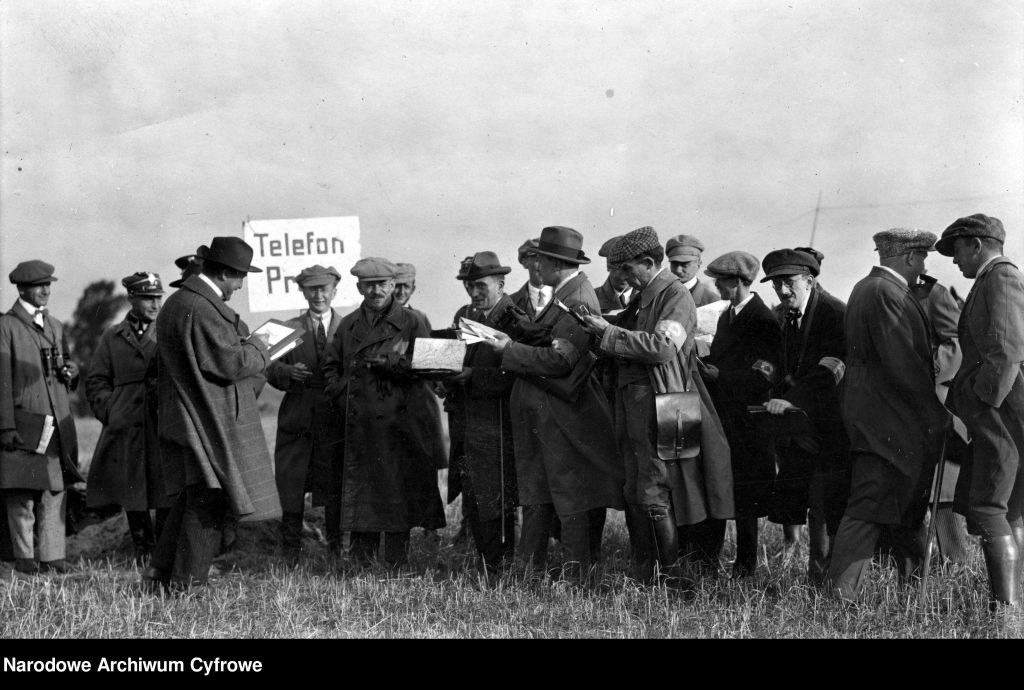 grupa ludzi, w tle tabliczka z napisem telefon