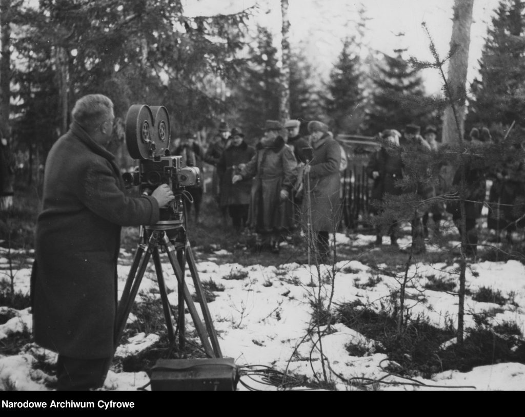mężczyzna z kamerą w zimowej scenerii lasu filmuje uczestników polowania