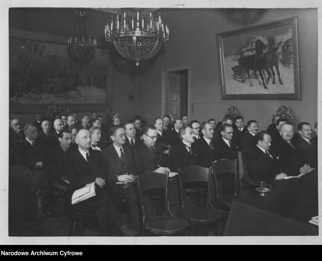 elegancko ubrani mężczyści siedzą rzędami w eleganckiej sali