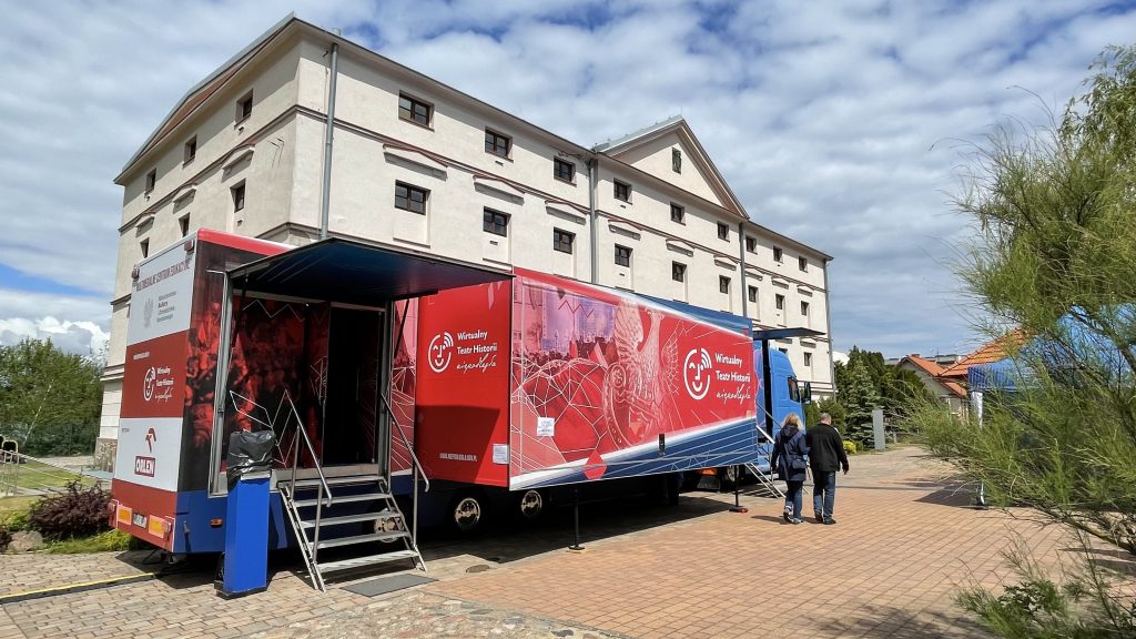 samochód Wirtualnego Teatru Historii na placu w Koninie przed białym budynkiem Muzeum Okręgowego