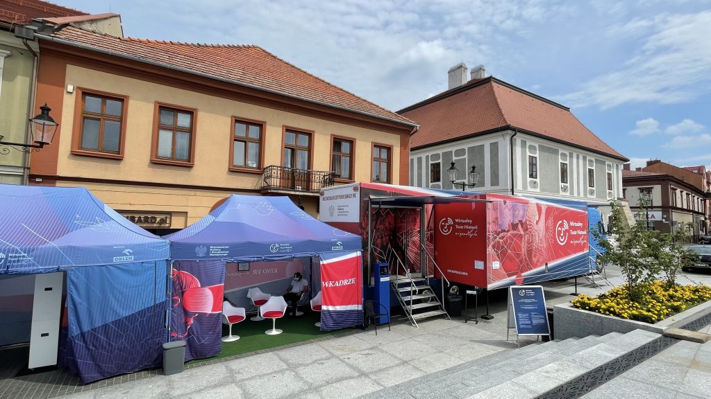samochód Wirtualnego Teatru Historii na tle pierzei kmieniczek rynku