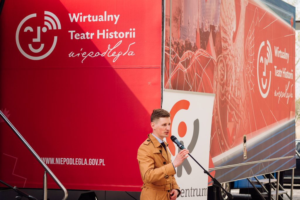 dyrektor kirejczyk przy mikrofonie przemawia przed rozłożonym mobilnym centrum edukacji