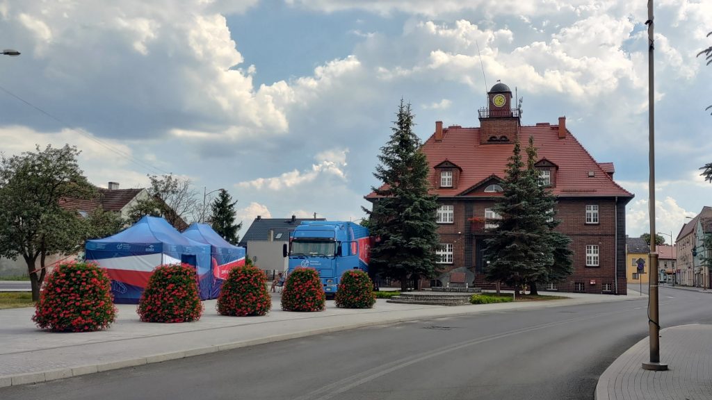 samochód Wirtualnego Teatru Historii na placu przed ratuszem, po prawej stronie ulica