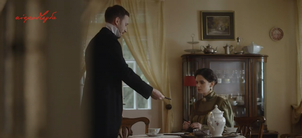 mężczyzna notariusz podaje elegancko ubranej kobiecie przy stole pióro