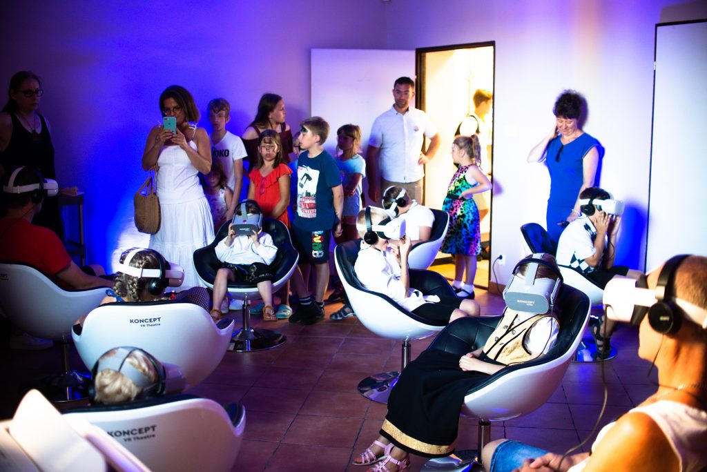 ludzie na fotelach z okularami VR podczas seansu