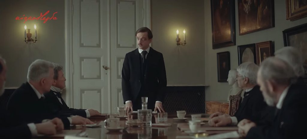 dmowski stoi przy stole podzczas przemowy przed politykami zgromadzonymi wokórł stołu