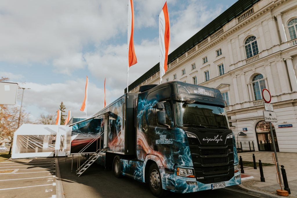 samochód iskier niepodległej z flagami na parkingu przed budynkiem