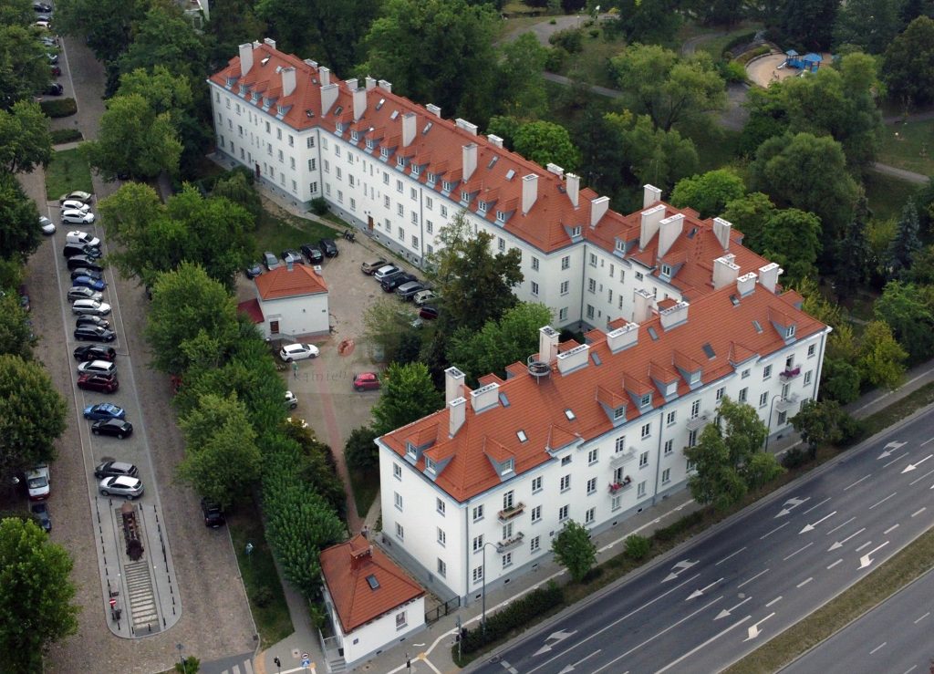 biały blok z czerwonym dachem zbudowany na planie litery L z lotu ptaka