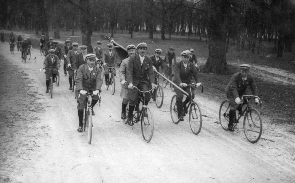 rowerzyści w peletonie jadący po drodze