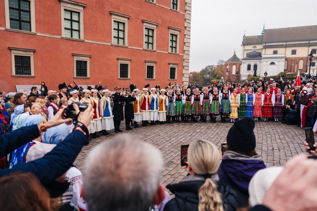 ludzie śpiewają hymn pod Zamkiem Królewskim w Warszawie