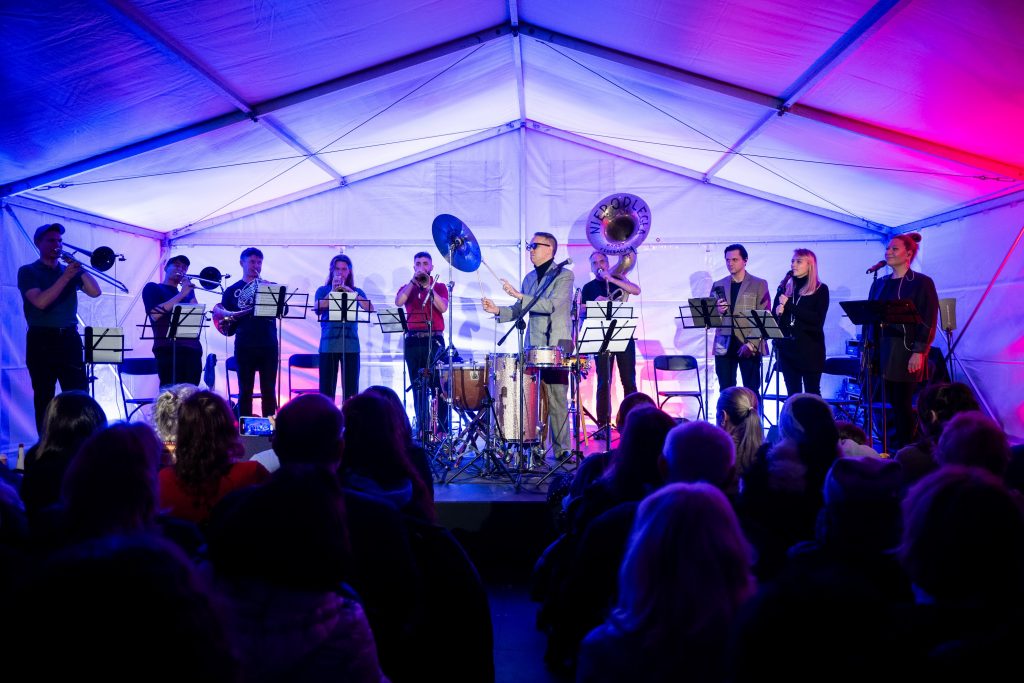 zespół i wokalista na scenie NMS, na piewszym planie zgromadzona publiczność