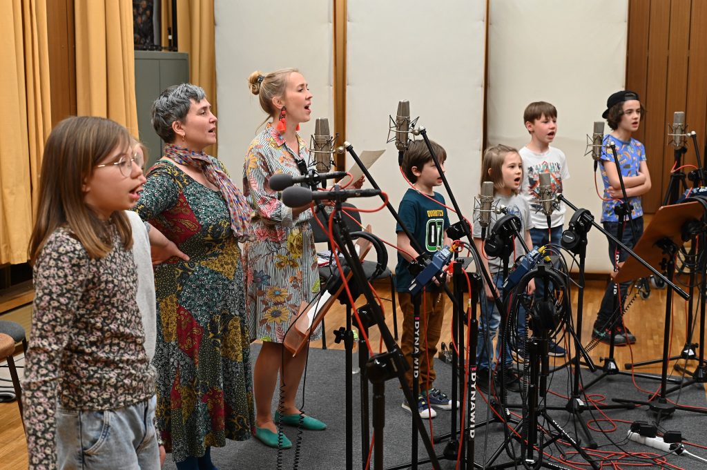 grupa dorosłych i dzieci przed mikrofonami podczas nagrania